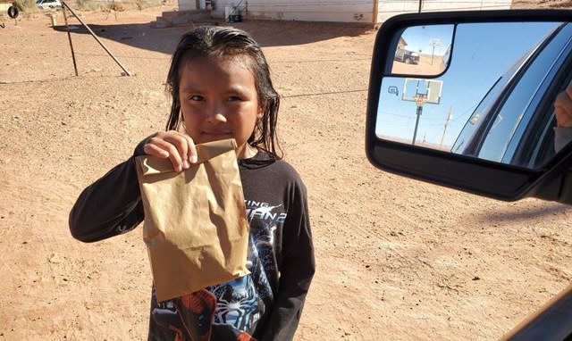 Child holding up a bag lunch received through our COVID-19 fund program